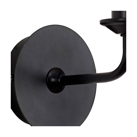 Close-up of the Banyan E14 Wall Light in matt black iron, showing the round wall plate, short curved arm, and bare candle lampholder against a white background.