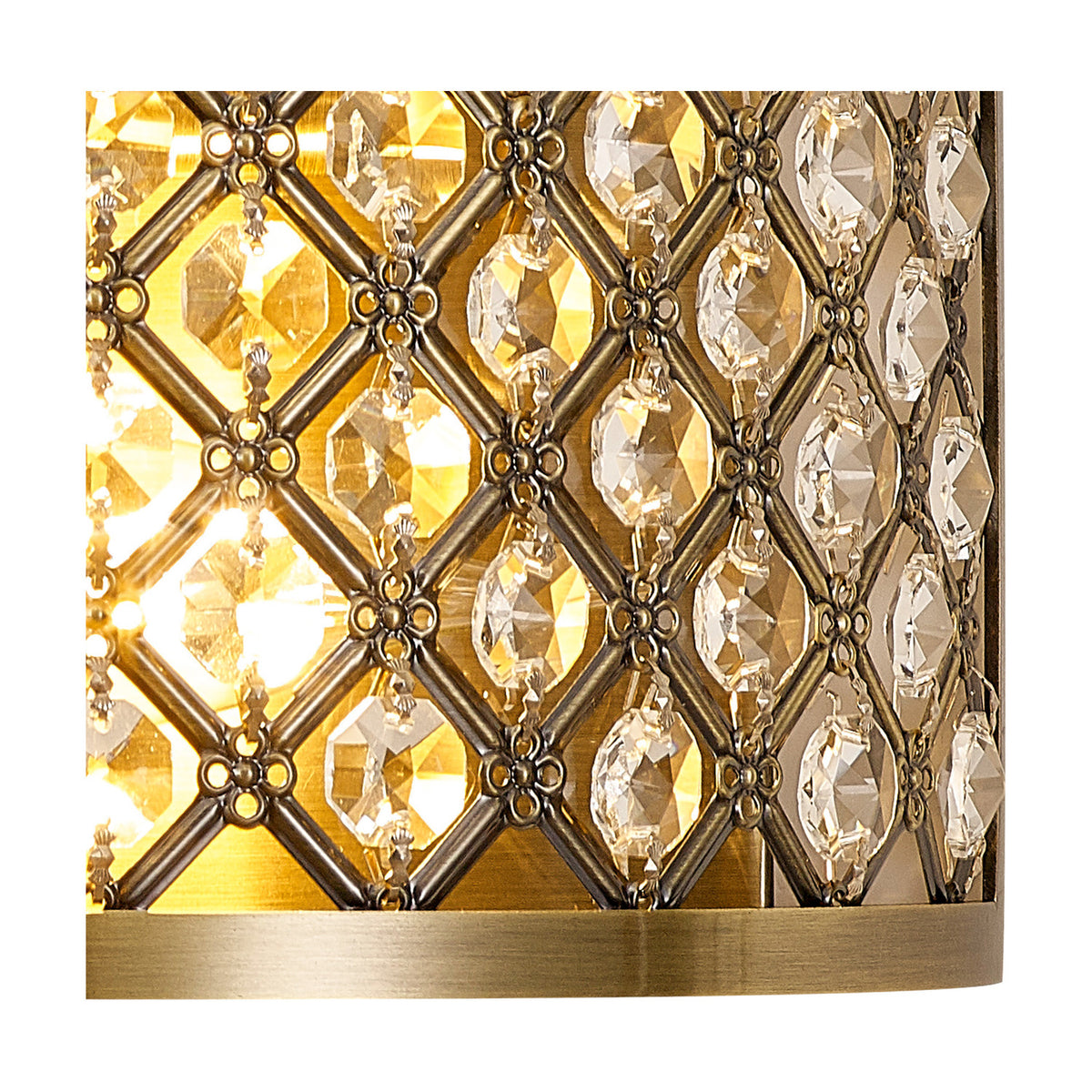 Close-up of the Sasha 2 Light E14 Wall Light in antique brass, showing a lattice of faceted crystal beads over a curved brass frame with illuminated glow beneath.