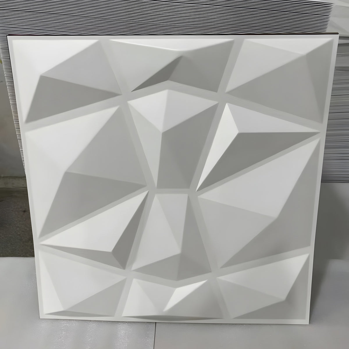 White PVC 3D wall panel, 50 x 50cm, with irregular pyramid facets in a geometric grid, shown upright against a plain light background.