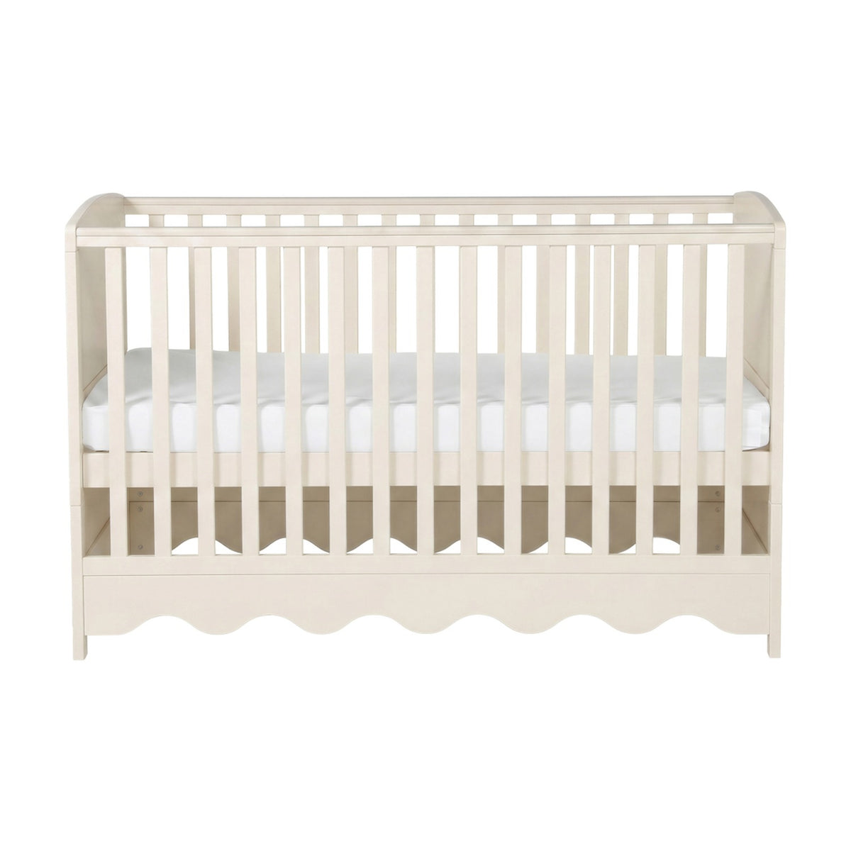 Dancer cot bed from the 3 piece nursery furniture set in Cashmere, cream MDF slatted frame with scalloped base panel and white mattress, shown on a plain white background.