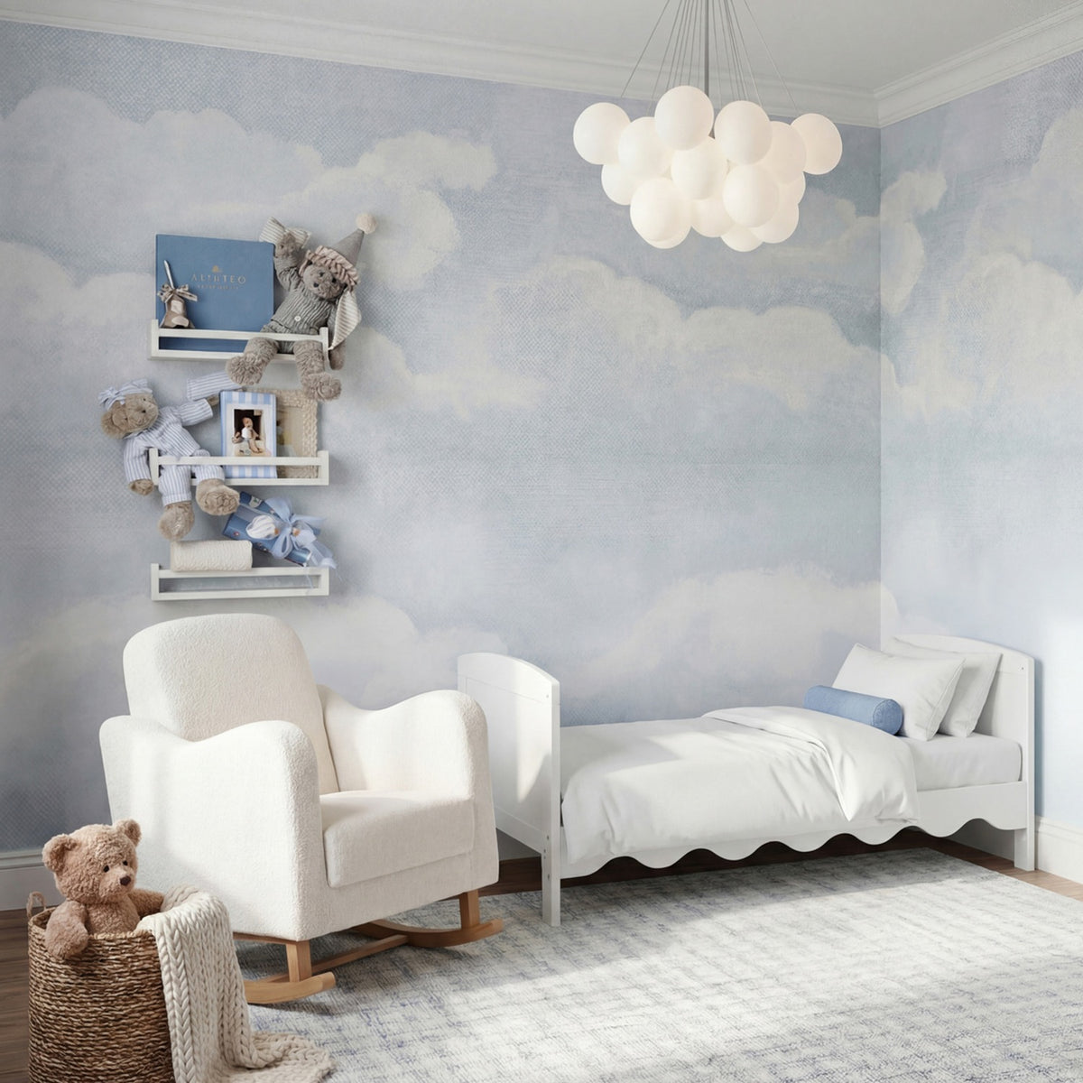 Dancer Convertible Cot Bed with scalloped white MDF frame, styled with white bedding in a cloud-themed nursery alongside a shelf, armchair and cot toys.