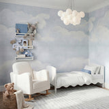 Dancer Convertible Cot Bed with scalloped white MDF frame, styled with white bedding in a cloud-themed nursery alongside a shelf, armchair and cot toys.
