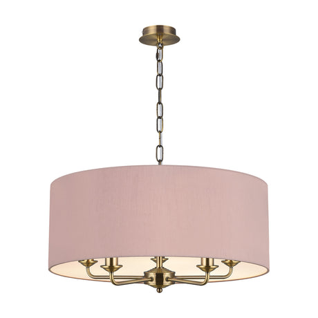 Banyan 5-light E14 pendant in antique brass with curved candle arms beneath a 60cm taupe drum shade with gold lining, chain suspension, shown on a white background.