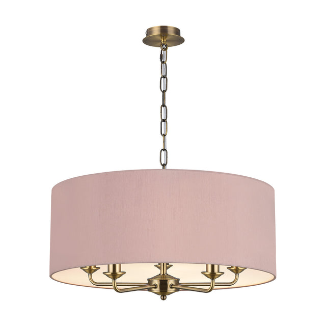 Banyan 5-light E14 pendant in antique brass with curved candle arms beneath a 60cm taupe drum shade with gold lining, chain suspension, shown on a white background.