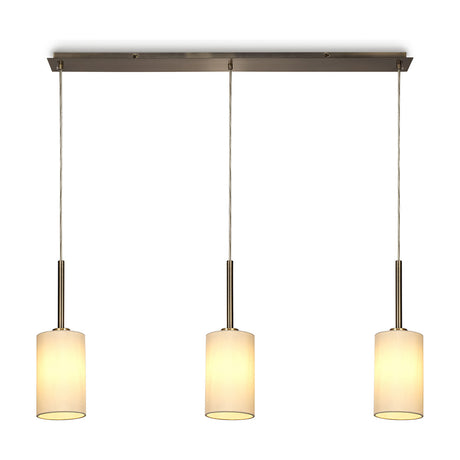 Baymont 3 Light E27 pendant light with ivory fabric cylinder shades on a slim antique brass linear bar, 1.07m drop, shown on a plain white background.