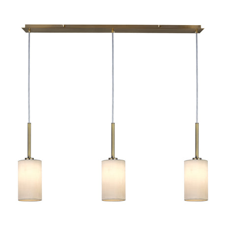 Baymont 3 Light Pendant with white faux silk drum shades on a linear antique brass bar and cords, shown on a plain white background.