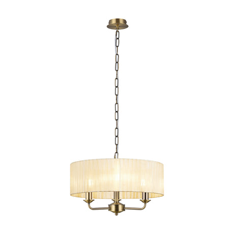 Banyan 3 Light E14 pendant light with cream organza drum shade and antique brass arms and chain, on a plain white background.
