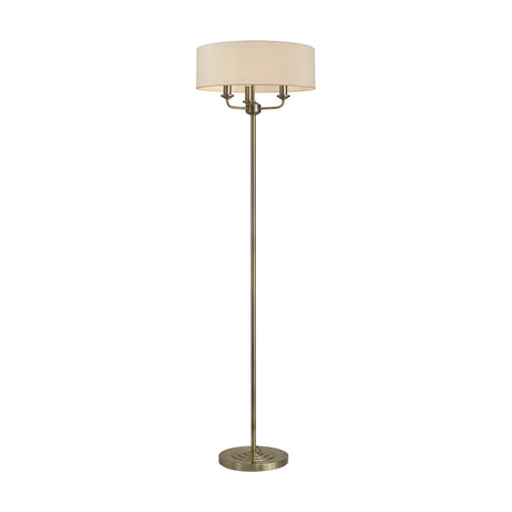 Banyan 3 Light E14 floor lamp with round ivory pearl fabric drum shade on a slim antique brass stem and circular base, shown on a plain white background.
