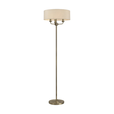 Banyan 3 Light E14 floor lamp with a 45cm nude beige drum shade on three arms, slim antique brass column and round base, shown on a plain white background.