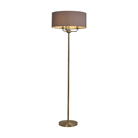 Banyan 3 Light E14 Floor Lamp with a grey faux silk drum shade on a slim antique brass column and weighted circular base, shown on a plain white background.