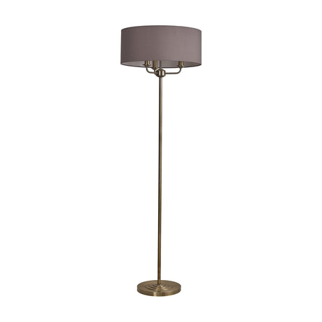 Banyan 3 Light E14 floor lamp with a round grey fabric drum shade on a slim antique brass column and weighted circular base, shown on a plain white background.