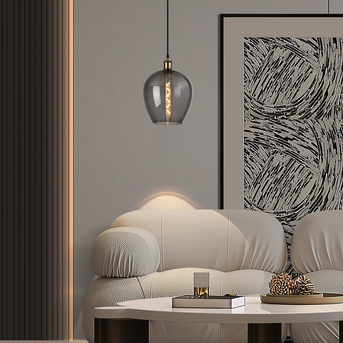 Cawdor E27 wine glass pendant light in smoke glass with antique brass fitting, 25cm shade, hung above a beige sofa in a living room setting.