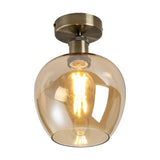Semi-flush ceiling light with a rounded 18cm amber glass shade and antique brass ceiling plate, fitted with a visible E27 bulb, shown on a white background.