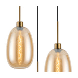 Amber glass pendant light with oval shade and antique gold fitting, shown with visible E27 filament bulb on a plain white background.