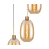 Close-up of amber glass pendant lights with antique gold fittings, showing tapered oval shades with visible filament bulbs against a plain white background.