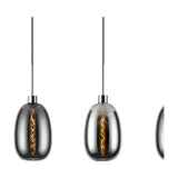 Lori pendant lights with smoke glass, elongated oval shades on black cords and polished chrome fittings, showing visible filament bulbs, against a white background.