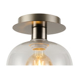 Close-up of the Lori E27 flush ceiling light with a round satin nickel plate and clear wine-glass shaped glass shade, showing the lit filament bulb inside.