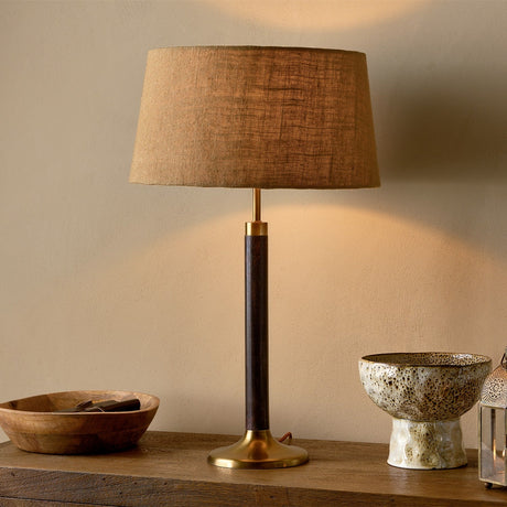 Digha Wooden Table Lamp with dark-stained mango wood column, antique brass base and cup, and a woven brown fabric shade, styled on a wooden sideboard.