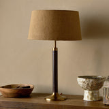 Digha Wooden Table Lamp Base with tan linen drum shade, dark stained mango wood column and antique brass base, shown on a sideboard beside a wooden bowl and ceramic bowl.