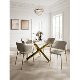 Dorchester dining chairs with wheat weave fabric upholstery and curved backrests, set on brushed gold metal legs, shown around a glass table with gold cross-base in a dining room.