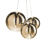 The Diverso LED Pendant Light - Gold features three modern glass globes with metallic reflections, suspended on slim wires against a white background, highlighting its elegant gold finish and energy-efficient LED design.