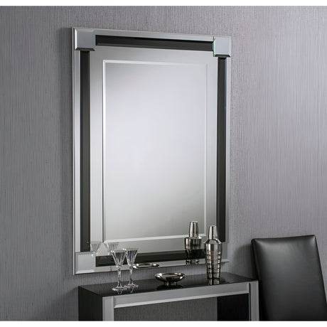 The Glowis Rectangle Wall Mirror in black, measuring 117x84cm, hangs above a sleek black console table adorned with glasses, a cocktail shaker, and a small tray. A partially visible black chair completes the setup against a textured gray wall, infusing the room with a modern touch.