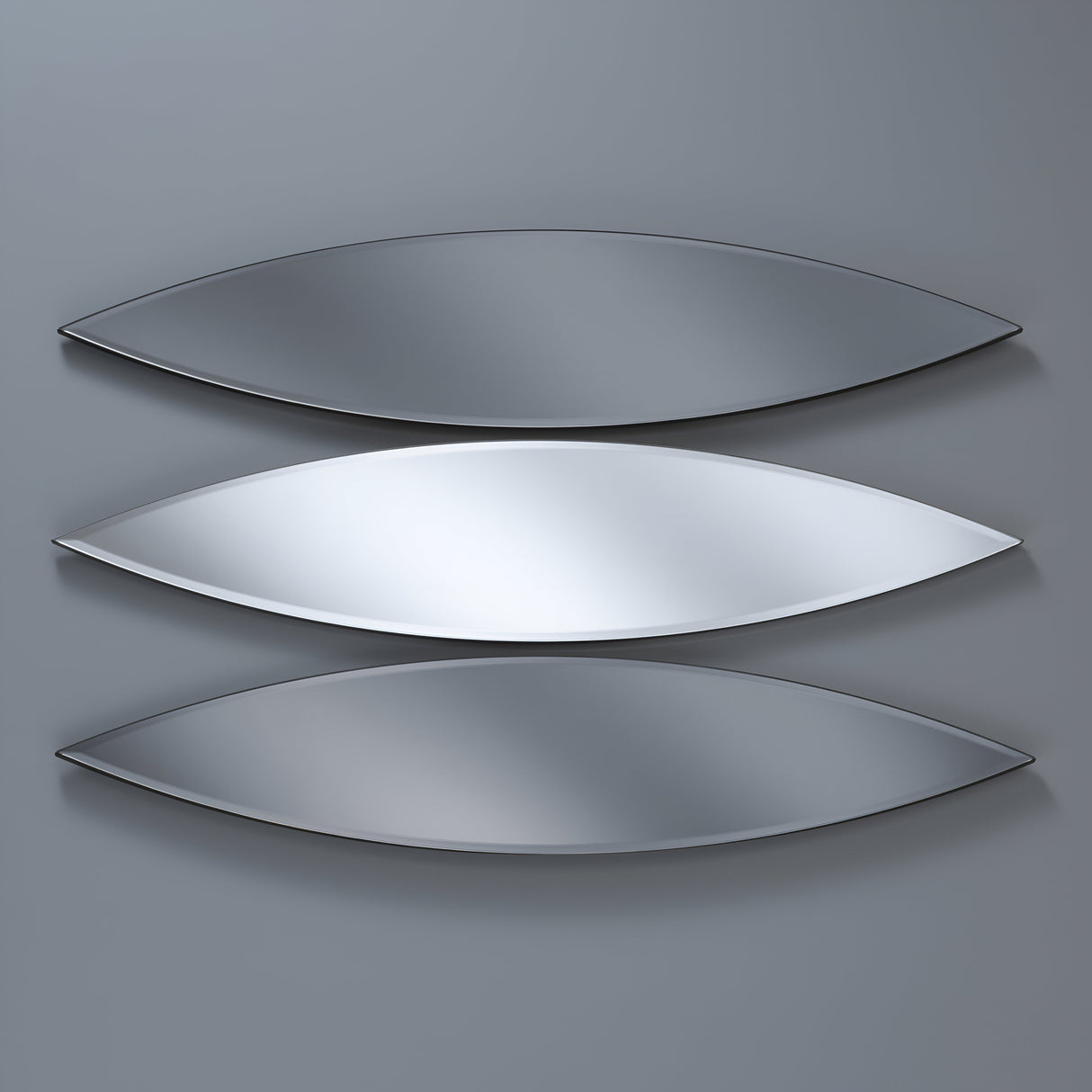 A set of three Velouria Oval Wall Mirrors (Grey & Silver, 130x30cm each) is mounted vertically on a gray wall. Each mirror subtly reflects the light, creating sleek elegance and embodying versatile interior design.