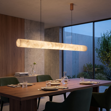 Zareon LED Large Linear Alabaster Chandelier in Soft White, a 1.5m cylindrical pendant suspended on twin cables above a wooden dining table with green chairs.