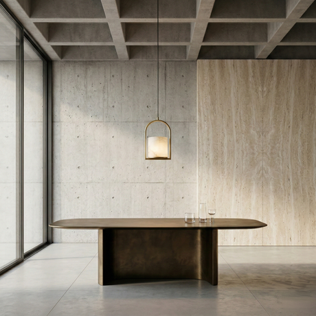 A minimalist dining room with a modern brown table, two clear glasses, large windows, concrete walls, light wood paneling, and the Halorin 1 Light Framed Alabaster Single Pendant in soft white & brushed brass. The space is bright and uncluttered.