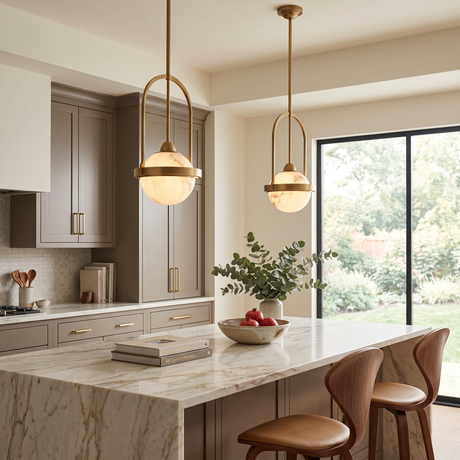 Calis Alabaster Single Pendant Light in Brushed Brass, spherical alabaster globe with arched brass frame, shown in pairs above a marble kitchen island.