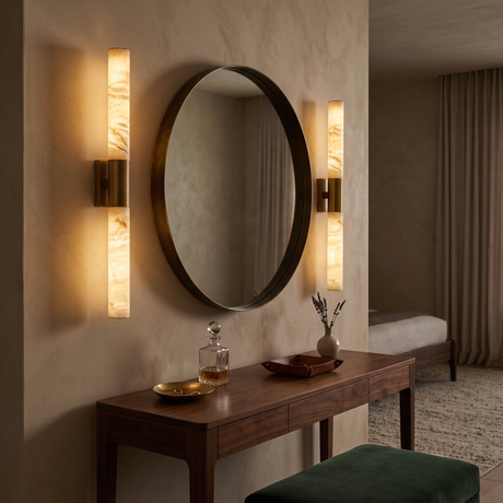 Niori Eryon LED Large Alabaster Wall Lights in brushed brass flanking a round bronze-framed mirror above a walnut console in a warm bedroom.