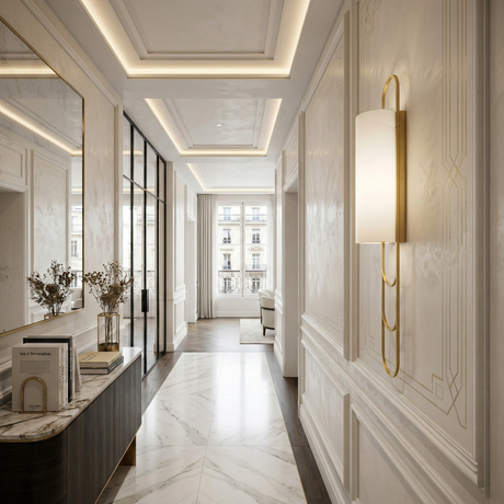 A bright, elegant hallway with marble floors, wall molding, a Catenis 2 Light Large Loop Frame Alabaster Wall Light in brushed brass & soft white, a console table with books and vases, a large mirror, and floor-to-ceiling windows letting in natural light.