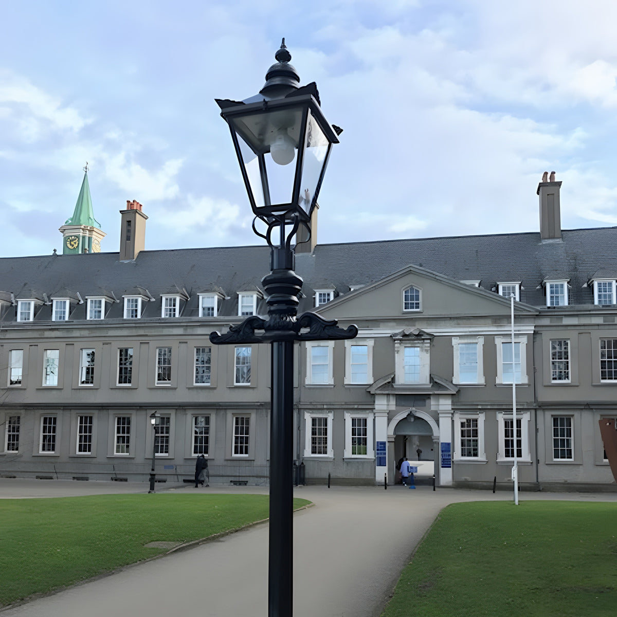 Victorian Cast Iron Lamp Post 3.5m in black with tapered four-sided lantern, stepped base and decorative bracket, shown outdoors on a paved courtyard before a grey period building.