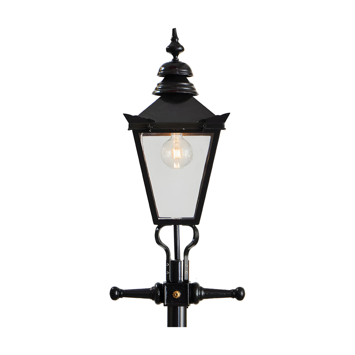 Victorian-style black cast iron lamp post with tapered four-sided lantern head, stepped crown, corner tips, cast finial and cross-arm bracket, shown against a plain white background.