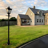 Victorian Cast Iron Lamp Post 2.6m in black with a four-sided lantern head, stepped crown and cast finial, shown on a lawn beside a house driveway.