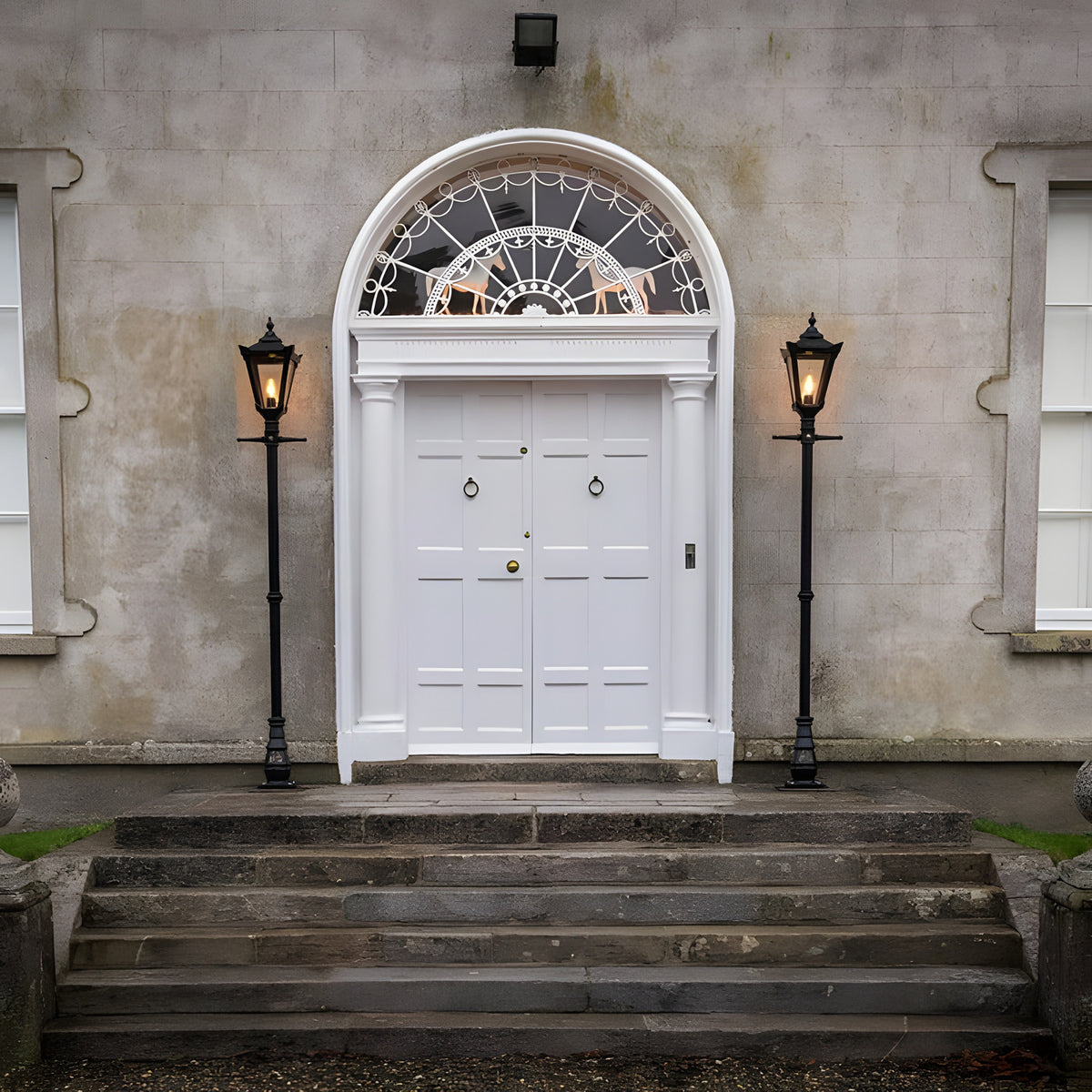 Victorian cast iron lamp post in black, 2.3m tall with tapered lantern head, shown lit beside a white panelled front door on a stone-pillared entrance.