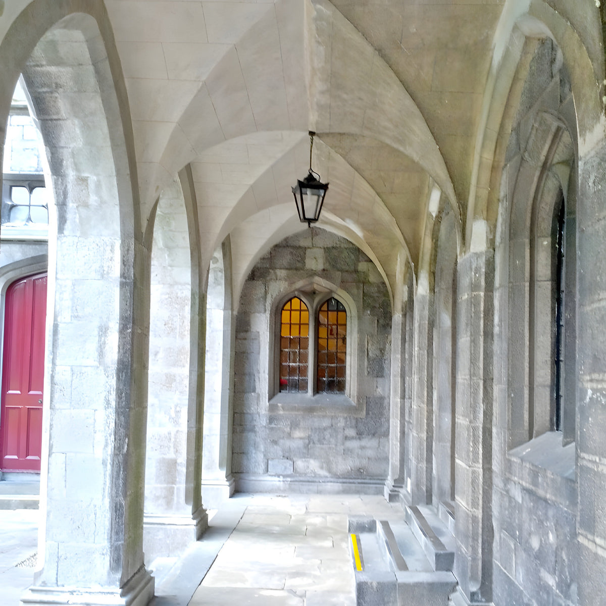 Medium Victorian cast iron hanging lantern in black, tapered four-sided glass head on a chain, shown suspended in a stone archway walkway.