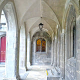 Medium Victorian cast iron hanging lantern in black, tapered four-sided glass head on a chain, shown suspended in a stone archway walkway.