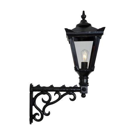 Medium Victorian wall lantern in black, tapered four-sided glass shade with cast finial, mounted on a decorative scroll bracket, shown on a plain white background.