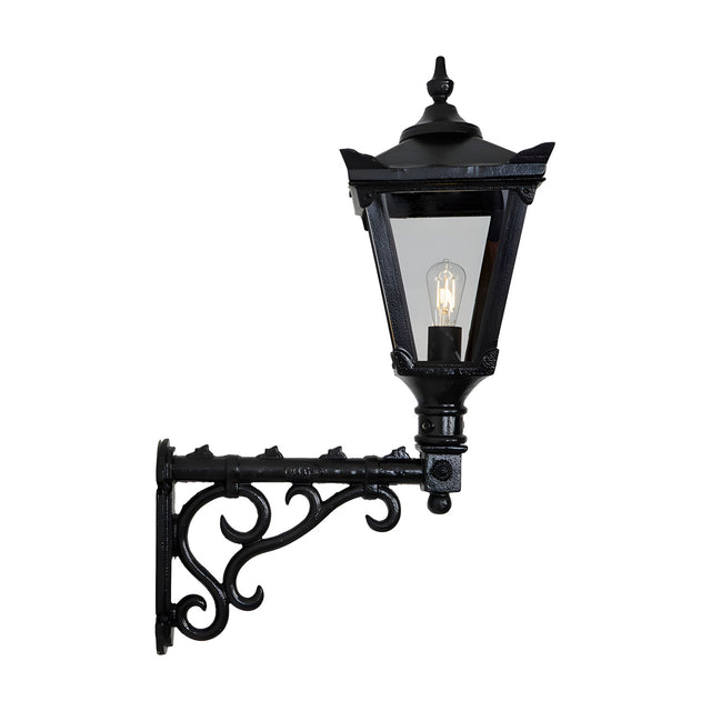 Medium Victorian wall lantern in black, tapered four-sided glass shade with cast finial, mounted on a decorative scroll bracket, shown on a plain white background.
