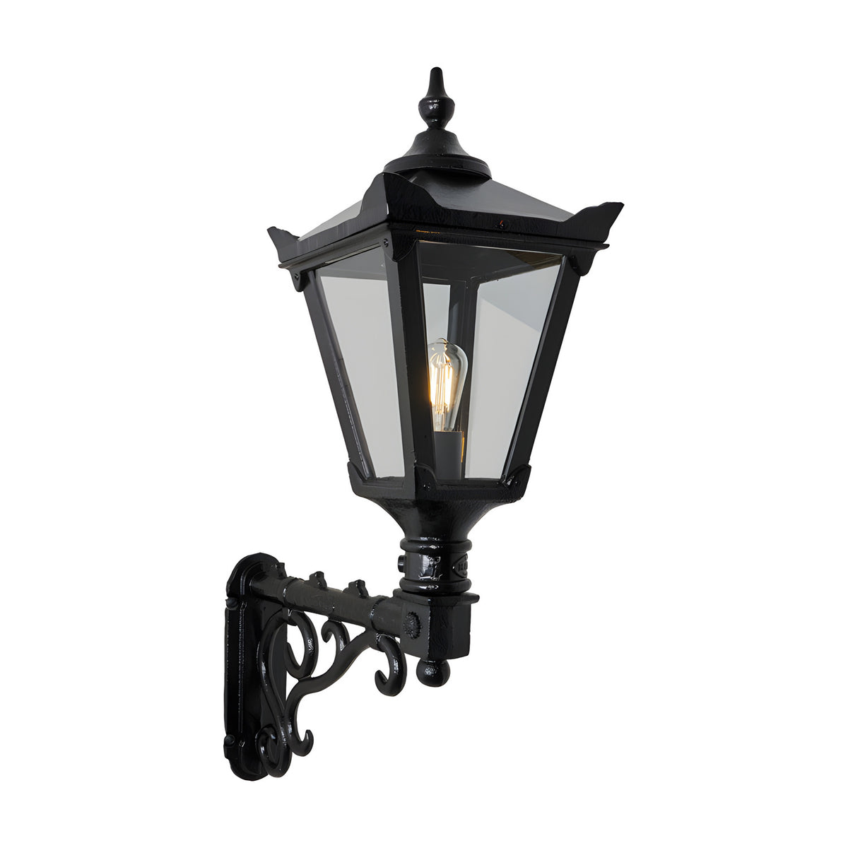 Medium Victorian wall lantern in black, a tapered four-sided glass lantern with cast finial mounted on a decorative scroll bracket, shown lit against a plain white background.