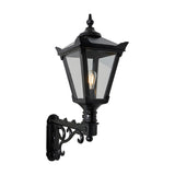 Medium Victorian wall lantern in black, a tapered four-sided glass lantern with cast finial mounted on a decorative scroll bracket, shown lit against a plain white background.