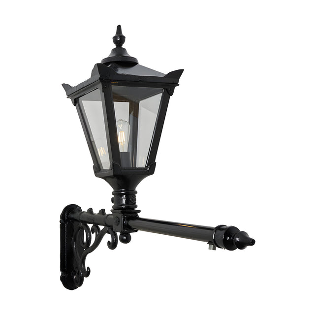 Victorian cast iron wall lantern in black with a tapered four-sided glass head, stepped crown, finial top, and scrolled bracket on a long extended arm, shown on a plain white background.