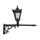 Victorian cast iron wall lantern in black with a tapered four-sided glass head, stepped crown, cast finial and scrolled long wall bracket, shown on a plain white background.