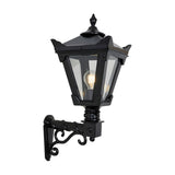 Small Victorian wall lantern in black with tapered four-sided glass head, stepped crown finial, and cast scroll bracket, shown lit on a plain white background.