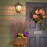 Small Victorian Cast Iron Half Lantern Wall Light in black, illuminated beside a grey front door with a floral wreath, on a light green panelled house exterior.