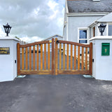 Small Victorian cast iron pillar light in black mounted on a stone gate pier, tapered four-sided lantern head with stepped crown and finial, flanking a wooden driveway gate.