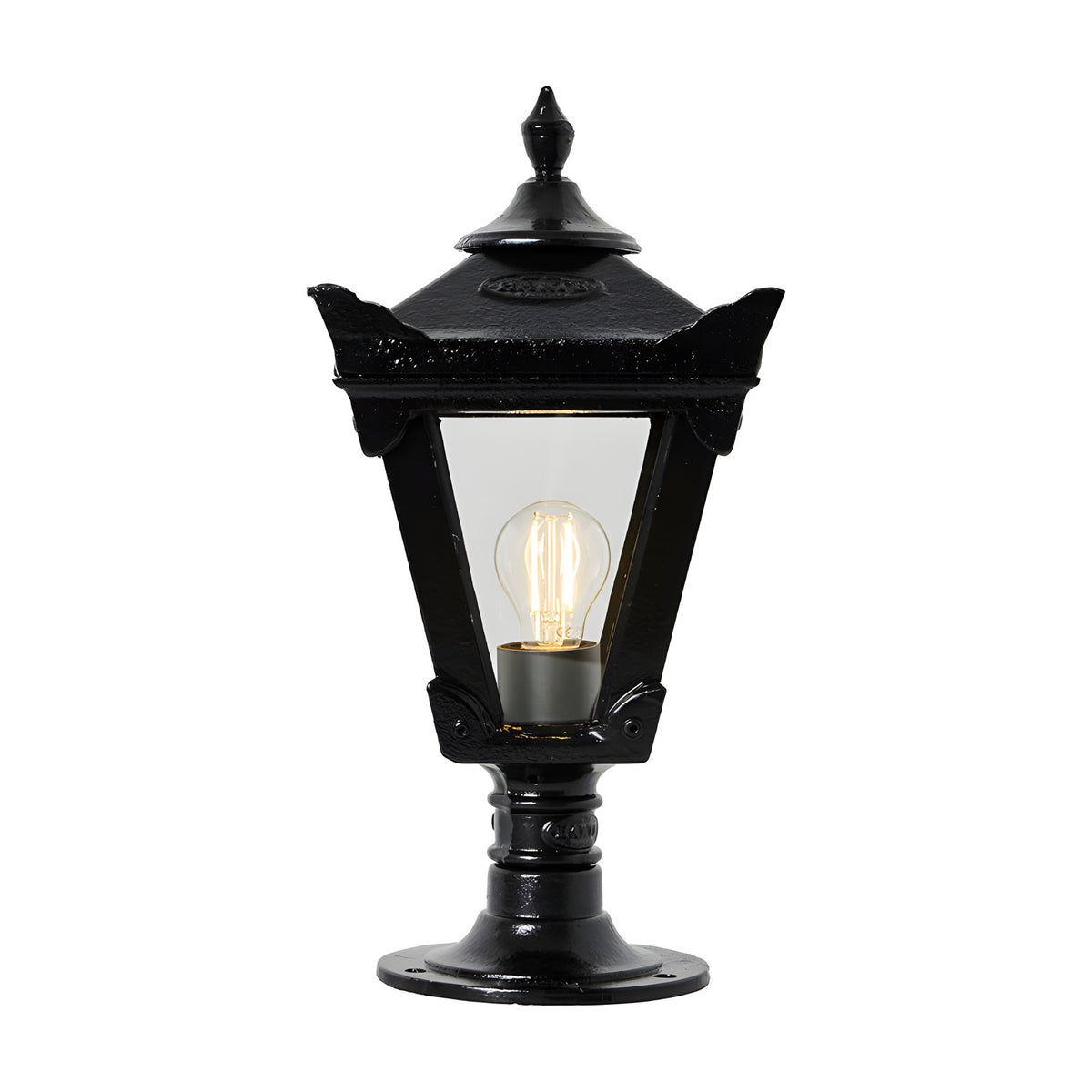 Small Victorian cast iron pillar light in black with tapered four-sided head, stepped crown, cast finial and clear glass panels showing an E27 bulb, on plain white background.