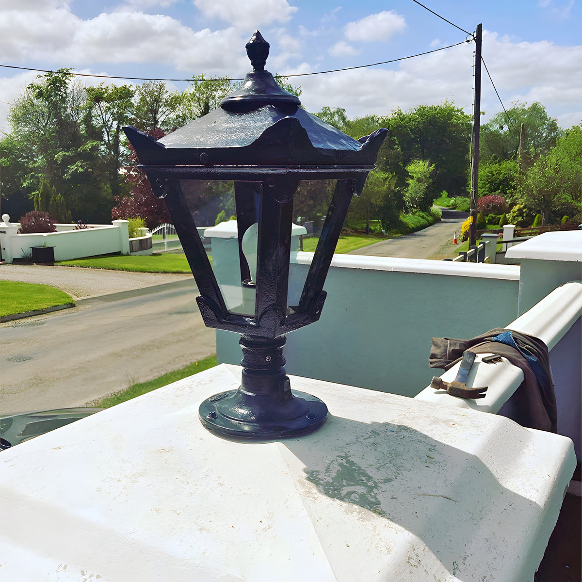 Small Victorian Cast Iron Pillar Light in black with tapered four-sided head, stepped crown and finial, mounted on a flat pier cap outdoors.