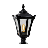Large Victorian cast iron pillar light in black, tapered four-sided glass head with stepped crown, corner tips, cast finial and pier cap base, lit E27 bulb visible, plain white background.